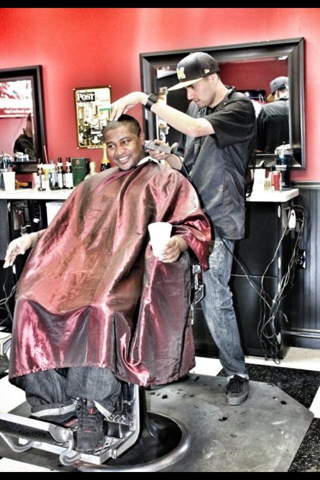 A barber at work with a smiling client inside Dappers Barbershop